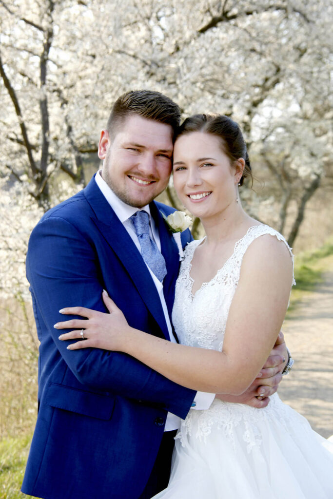 Romantisk bryllupsfoto med blomstrende træer i baggrunden.